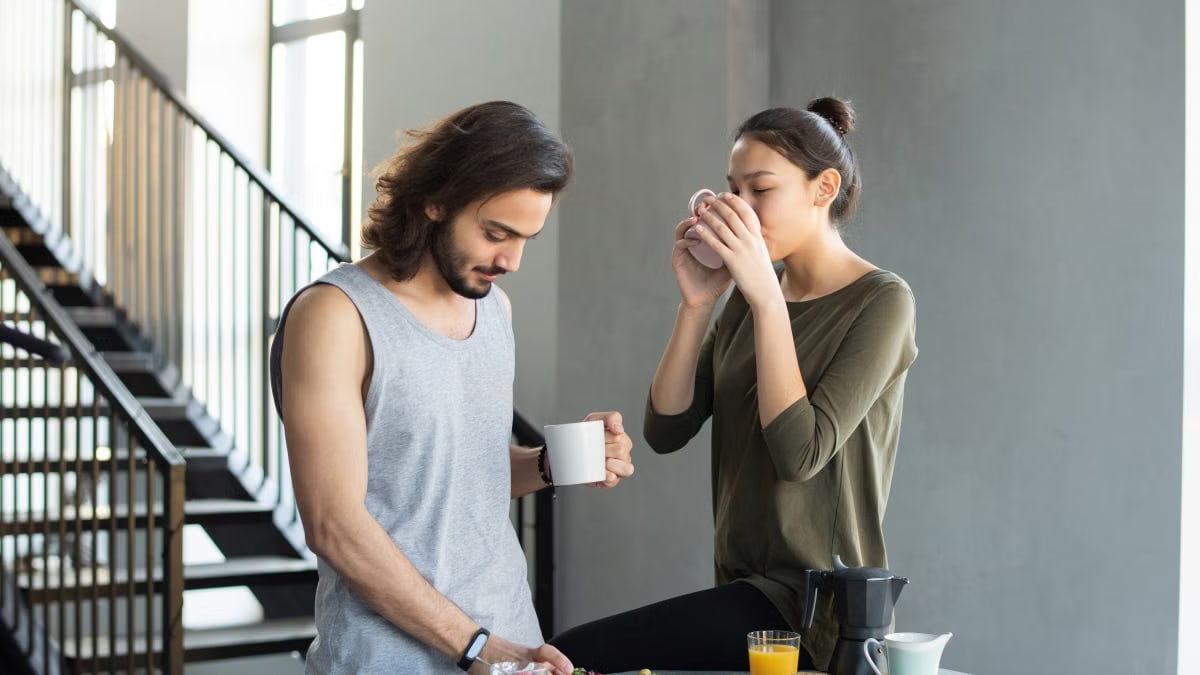 A couple enjoying a cozy breakfast with coffee and juice in their modern home kitchen.